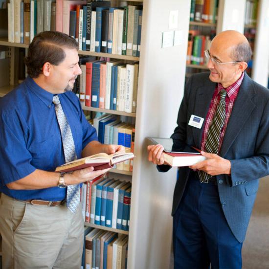 两个男教授在图书馆拿着书.