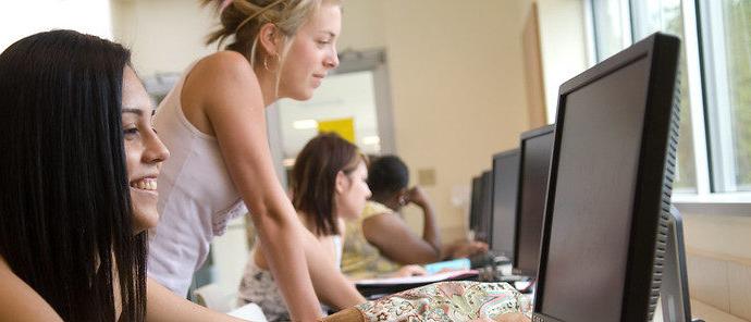 一名女学生和其他学生一起在不同的电脑前看电脑.