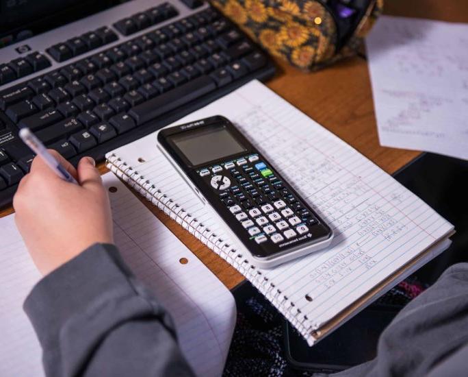 一个学生桌上的螺旋装订的笔记本上放着一个计算器.